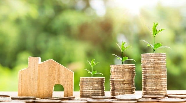 image of piles of coin and a small wooden home representing how we can save money and energy by making small changes in our homes